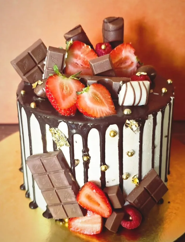 Drip cake réalisé par Kelsy : coulure de chocolat, fraises, carrés de chocolat et perles dorées